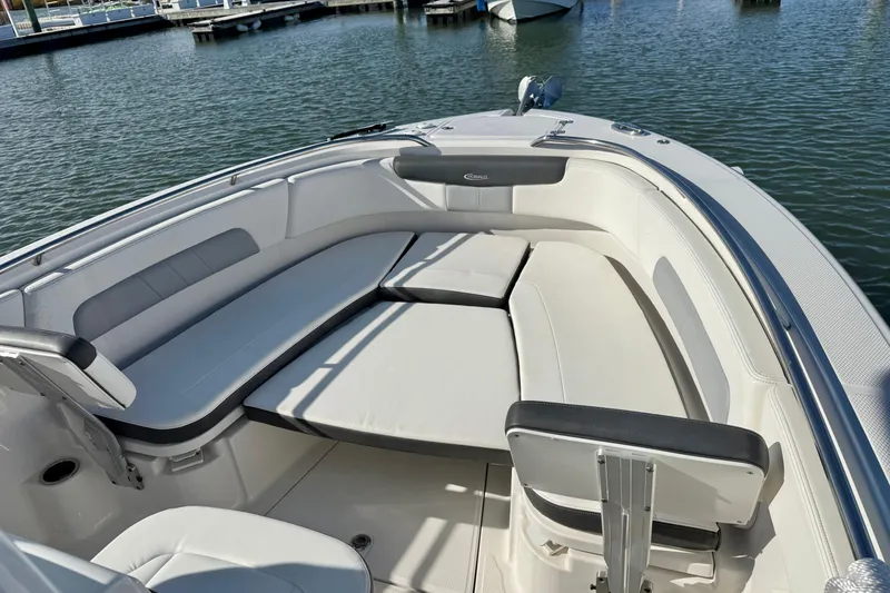 Slide: The Image of 2022 Robalo R242 Explorer boat interior with cushioned seating in a marina setting. - 2