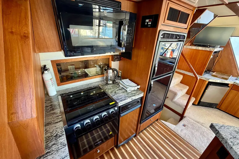 Slide: The Image of Luxurious 1995 Bayliner 4788 Pilot House Motoryacht kitchen with modern appliances and wood accents. - 17