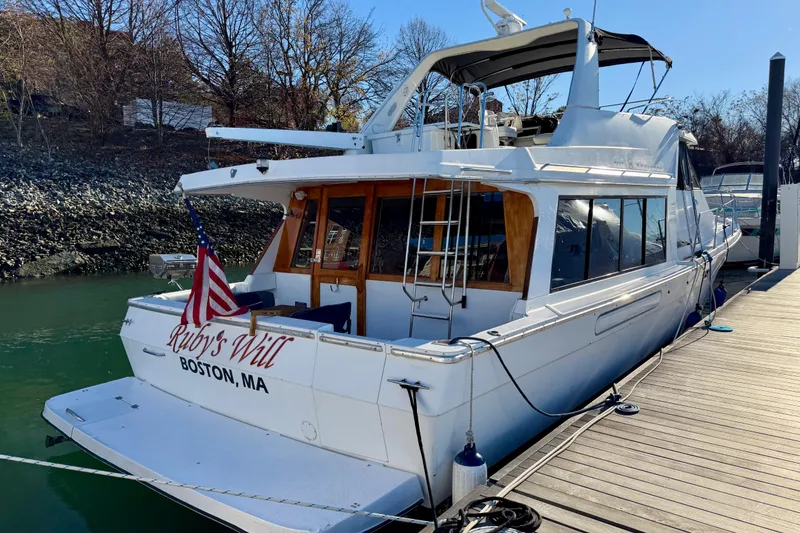 Slide: The Image of 1995 Bayliner 4788 Pilot House Motoryacht docked, displaying American flag, named "Ruby's Will." - 2