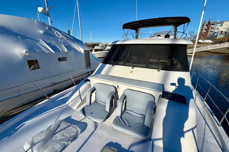 Slide: The Image of 1995 Bayliner 4788 Pilot House Motoryacht with deck chairs, docked in marina. - 4