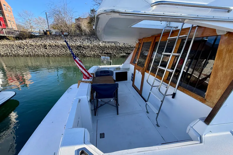 Slide: The Image of 1995 Bayliner 4788 Pilot House Motoryacht deck with American flag and seating area. - 5