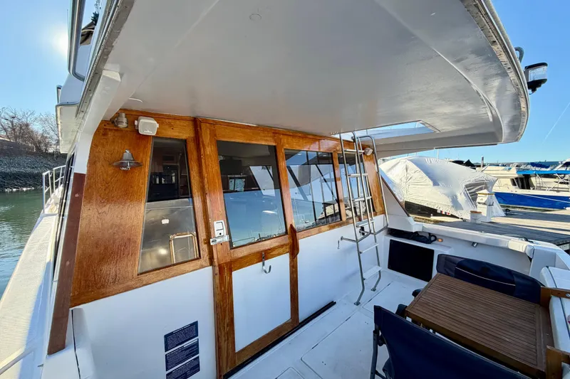 Slide: The Image of 1995 Bayliner 4788 Pilot House Motoryacht with wooden doors and outdoor seating area. - 6