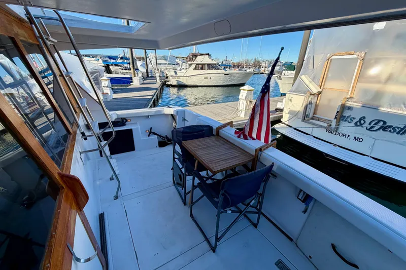 Slide: The Image of 1995 Bayliner 4788 Pilot House Motoryacht docked, featuring outdoor seating and American flag. - 7