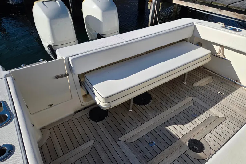 Slide: The Image of 2013 Boston Whaler 320 Outrage boat interior with cushioned seating and twin outboard engines. - 14