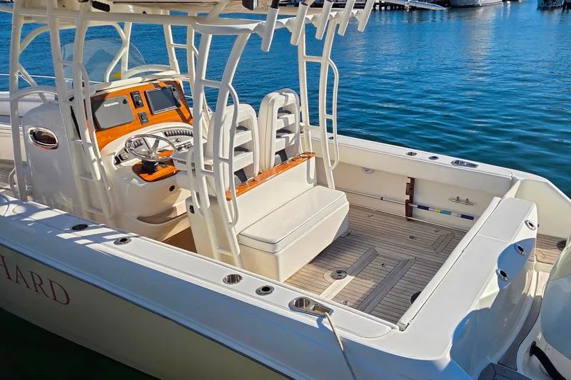 Slide: The Image of 2013 Boston Whaler 320 Outrage boat interior with helm and seating, docked on calm water. - 15
