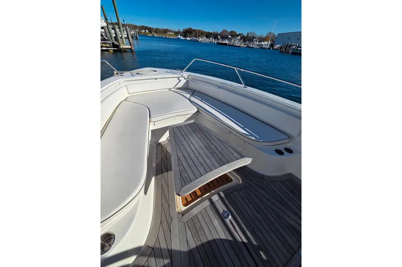 Slide: The Image of 2013 Boston Whaler 320 Outrage boat interior with seating and table, docked by the water. - 11