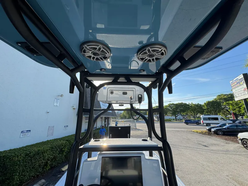 Slide: The Image of 2025 Yellowfin 24 CE boat interior with speakers and console, parked outdoors. - 12
