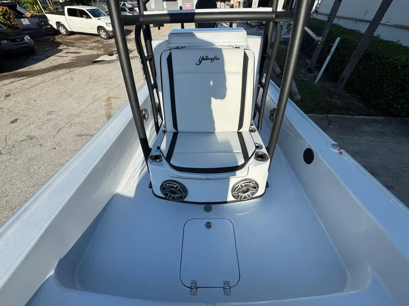 Slide: The Image of 2025 Yellowfin 24 CE boat interior with seating and speakers, parked outdoors. - 14