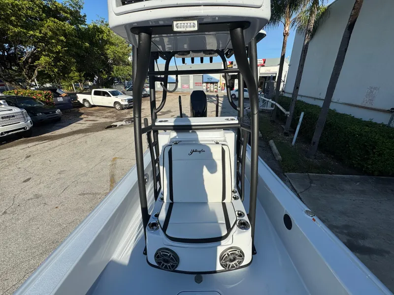 Slide: The Image of 2025 Yellowfin 24 CE boat interior with seating and speakers, parked outdoors. - 15