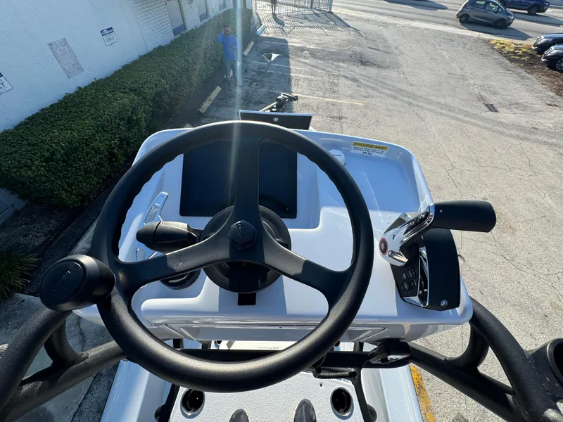 Slide: The Image of 2025 Yellowfin 24 CE boat helm with steering wheel and controls, parked outdoors. - 17