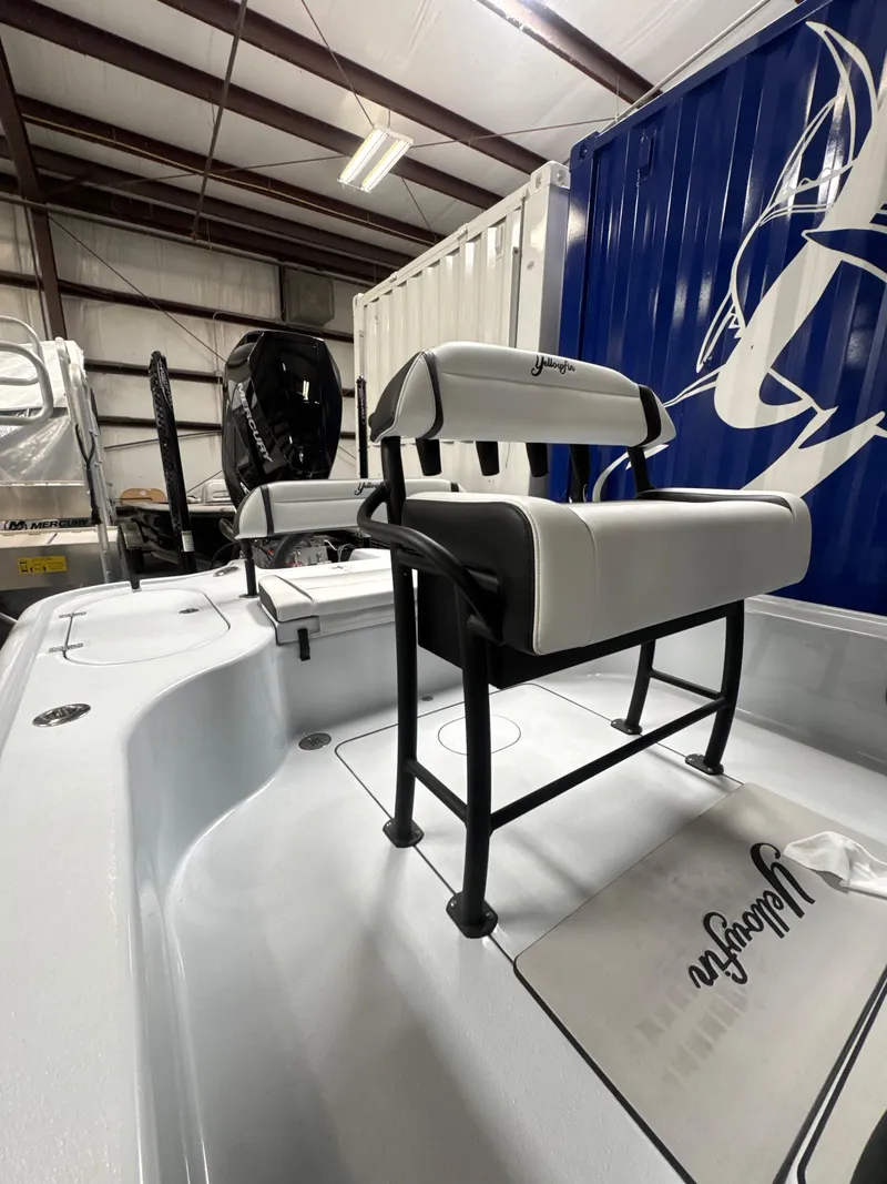Slide: The Image of 2025 Yellowfin 24 CE boat interior with seating and storage in a warehouse setting. - 7