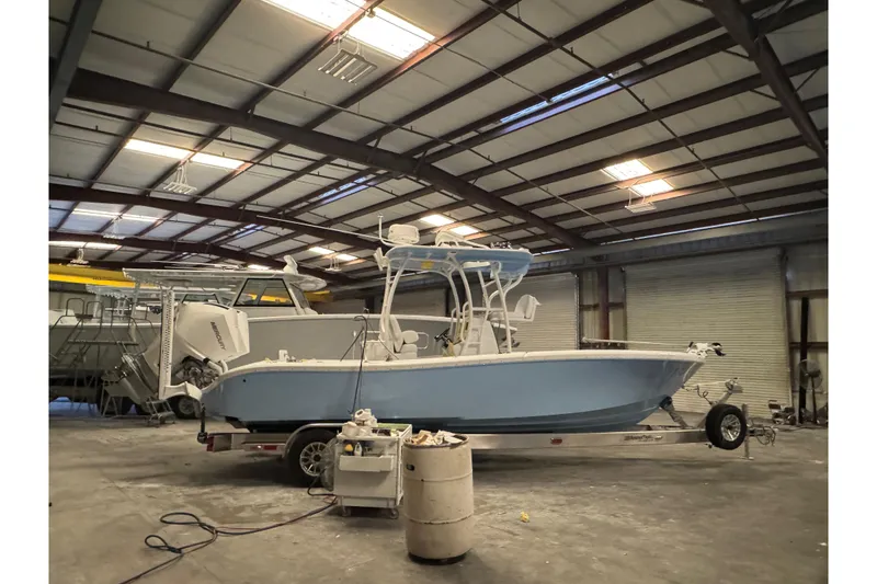 The Image of 2026 Yellowfin 26 Hybrid boat on trailer at a boat center, under a clear sky. - 0