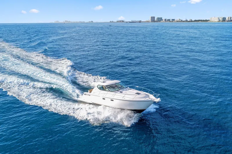 Slide: The Image of 2008 Tiara Yachts 4300 Sovran cruising on open blue ocean near city skyline. - 9