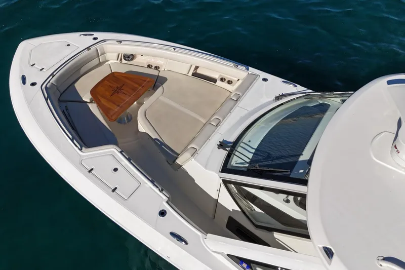 Slide: The Image of 2022 Boston Whaler 380 Realm boat with spacious seating and wooden table on deck. - 10