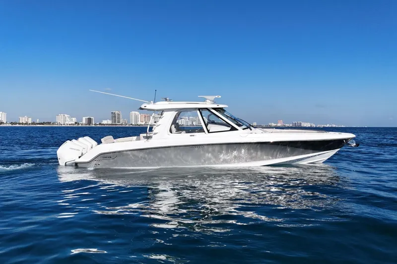 Slide: The Image of 2022 Boston Whaler 380 Realm cruising on blue ocean near city skyline. - 2