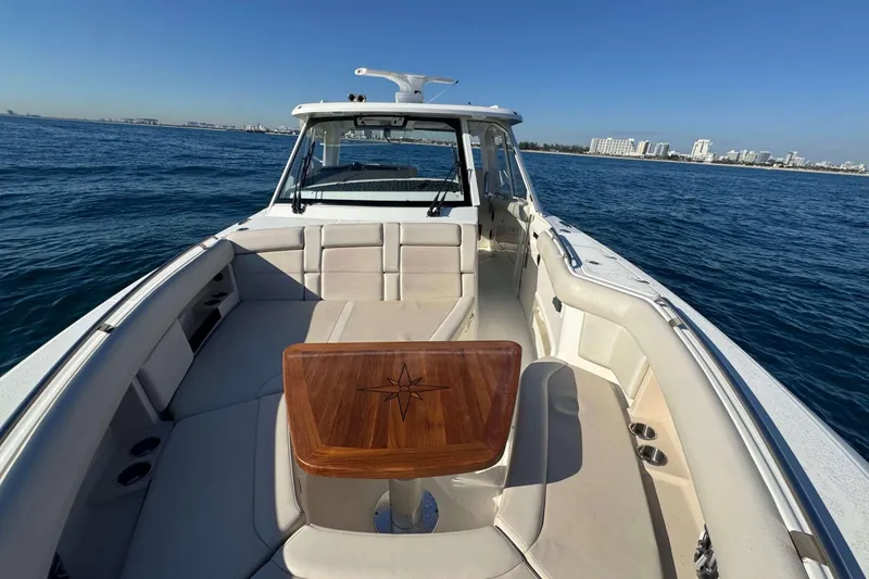 Slide: The Image of 2022 Boston Whaler 380 Realm boat on open water, featuring spacious seating and wooden table. - 26