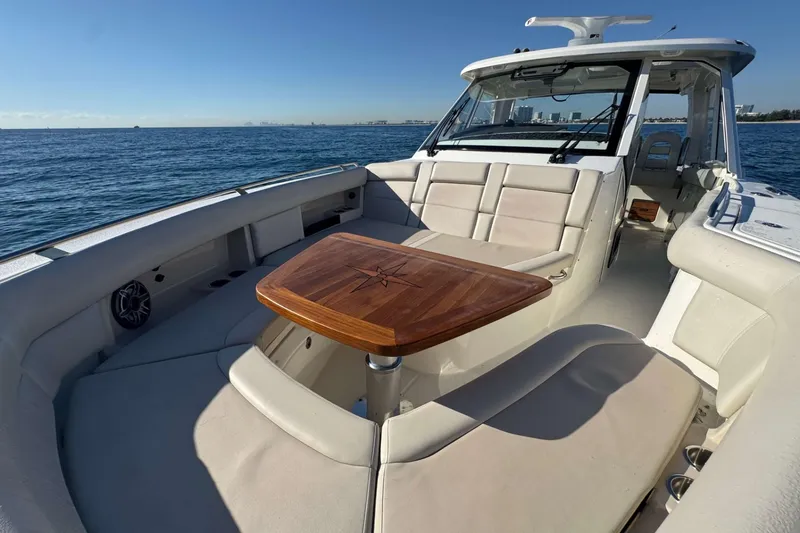 Slide: The Image of 2022 Boston Whaler 380 Realm boat interior with luxurious seating and wooden table on open water. - 27