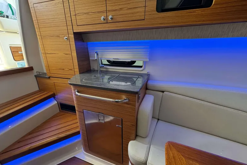 Slide: The Image of Interior of 2022 Boston Whaler 380 Realm with modern kitchenette and ambient lighting. - 38