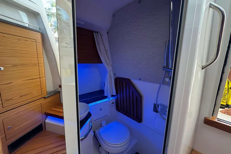 Slide: The Image of Interior of 2022 Boston Whaler 380 Realm boat, featuring a compact bathroom with wooden cabinetry. - 40