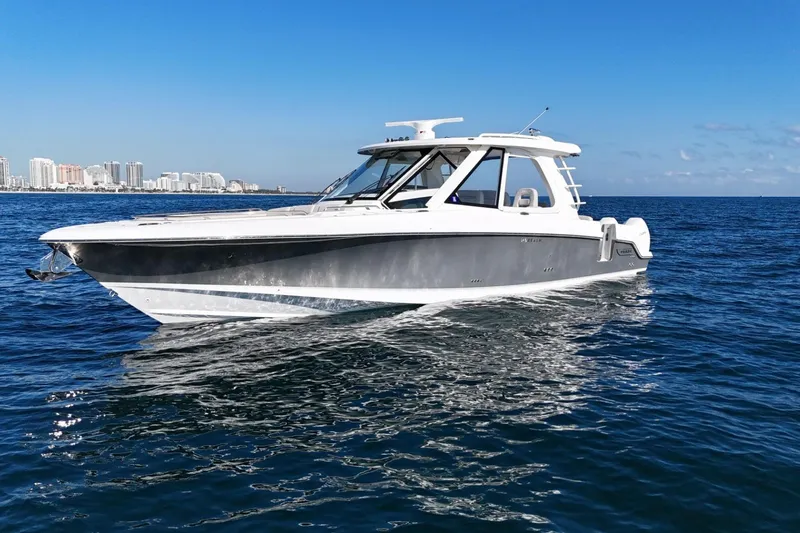Slide: The Image of 2022 Boston Whaler 380 Realm boat cruising on open water with city skyline in background. - 5