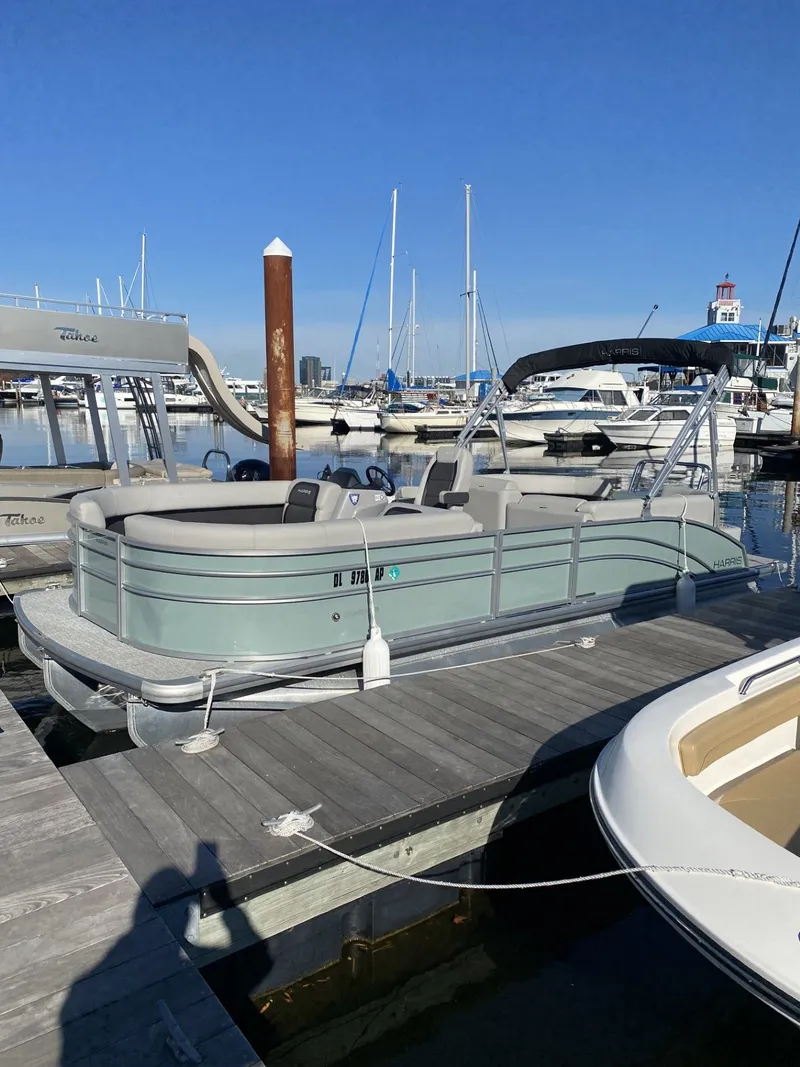 The Image of 2025 Harris FloteBote HCX23 pontoon boat docked at marina under clear blue sky. - 0