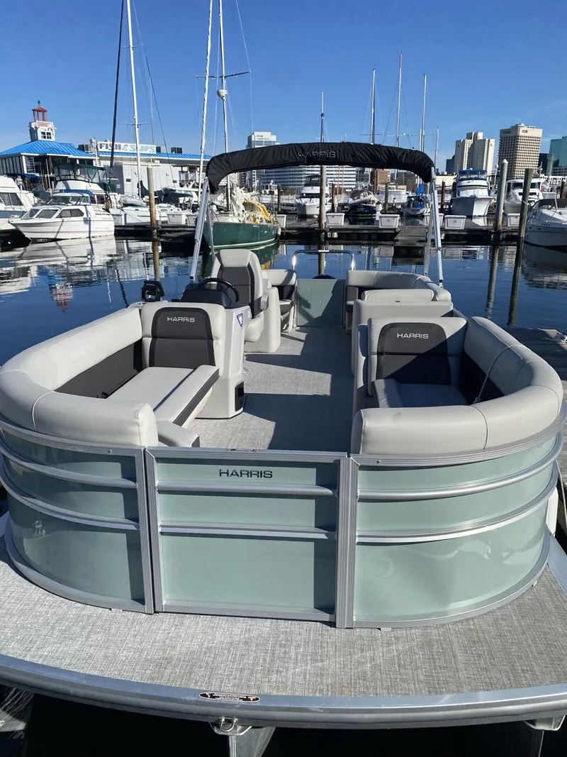 Slide: The Image of 2025 Harris FloteBote HCX23 pontoon boat docked at marina, featuring spacious seating. - 2