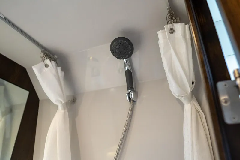 Slide: The Image of Shower area in 2022 Cruisers Yachts 38 GLS with white curtains and handheld showerhead. - 40