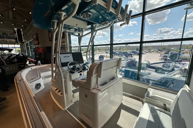 Slide: The Image of 2026 Mako 24 APEX boat interior in showroom with large windows and modern controls. - 6