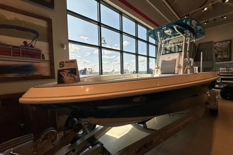 Slide: The Image of 2026 Mako 24 APEX boat displayed indoors with large windows and promotional materials. - 2
