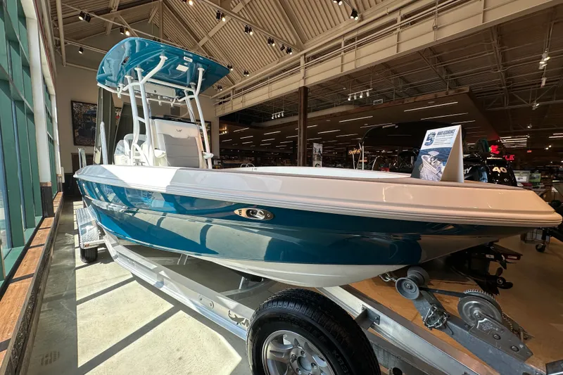 Slide: The Image of 2026 Mako 24 APEX boat displayed indoors on a trailer. - 1