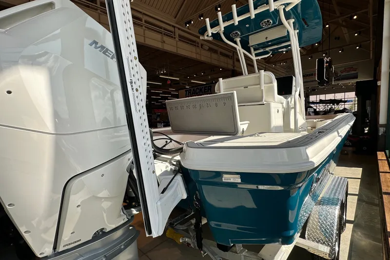 Slide: The Image of 2026 Mako 24 APEX boat with powerful engine, displayed indoors on a trailer. - 3