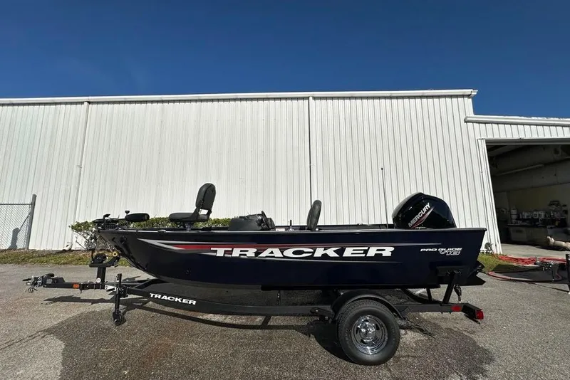 Slide: The Image of 2026 Tracker Pro Guide V-16 SC boat on trailer, parked outside a white building. - 46