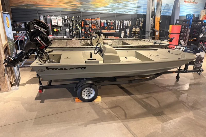 The Image of 2026 Tracker Grizzly 1648 SC boat displayed in a showroom with Mercury outboard motor. - 0
