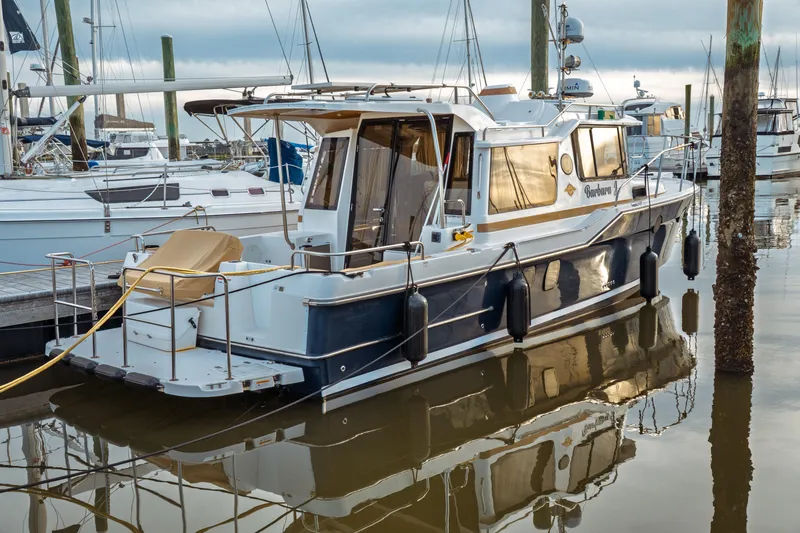 The Image of 2022 Ranger Tugs R-29 S docked at marina, reflecting on calm water. - 0