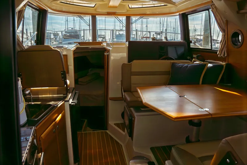 Slide: The Image of Interior of 2022 Ranger Tugs R-29 S, featuring dining area and kitchenette with marina view. - 16