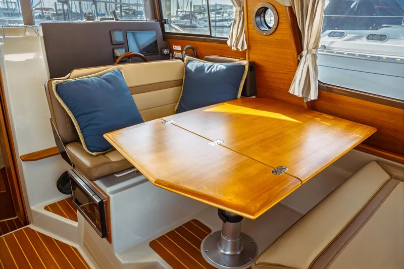 Slide: The Image of 2022 Ranger Tugs R-29 S interior with wooden table and cushioned seating. - 17