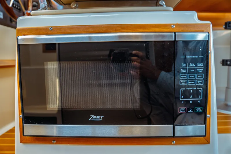 Slide: The Image of Microwave oven in 2022 Ranger Tugs R-29 S boat interior, featuring wood trim and digital controls. - 19