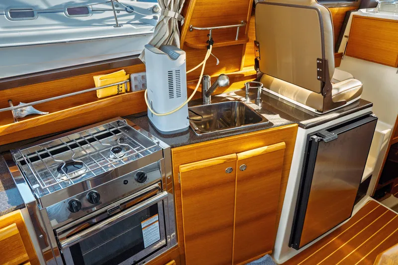 Slide: The Image of 2022 Ranger Tugs R-29 S galley with stove, sink, and compact refrigerator. - 28