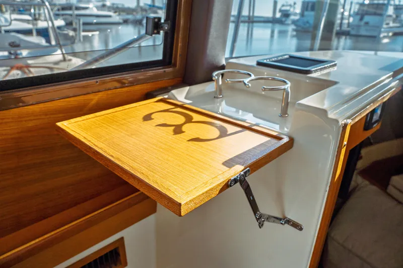 Slide: The Image of 2022 Ranger Tugs R-29 S interior with wooden fold-out table and cup holders. - 30