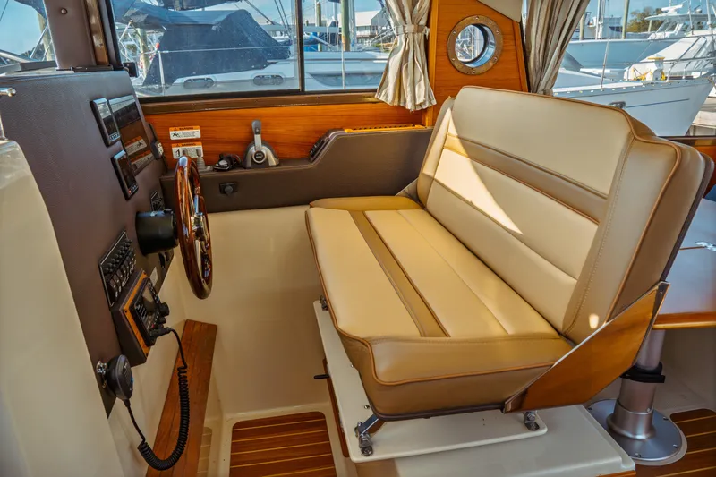 Slide: The Image of 2022 Ranger Tugs R-29 S helm with beige seating and wooden steering wheel. - 32