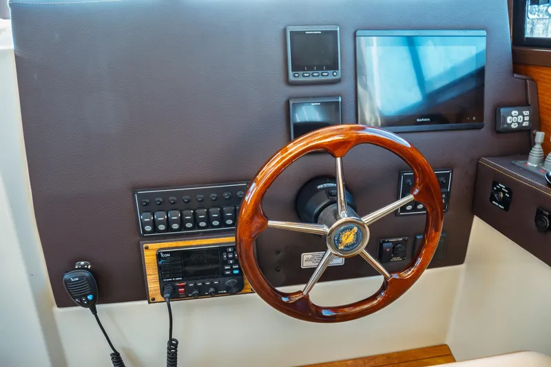 Slide: The Image of 2022 Ranger Tugs R-29 S helm with wooden steering wheel and navigation controls. - 33