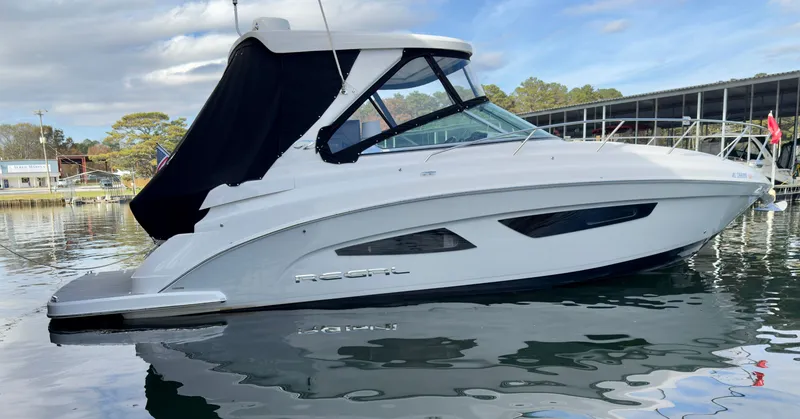 The Image of 2020 Regal 33 Express boat docked on calm water, featuring sleek design and black canopy. - 0