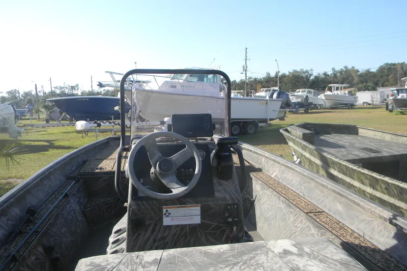 Slide: The Image of 2020 G3 Gator Tough 18 CC boat, camo interior, parked in a marina with other boats. - 7
