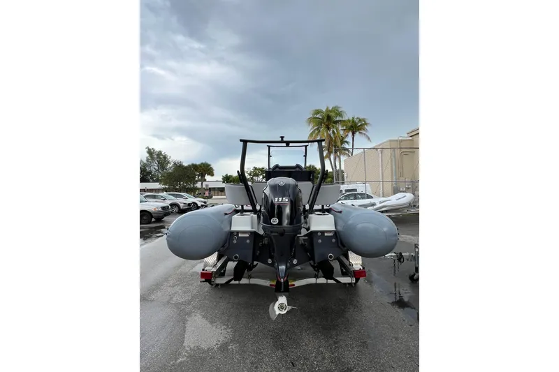 Slide: The Image of 2025 Zodiac Open 5.5 boat with outboard motor, parked outdoors on a cloudy day. - 3