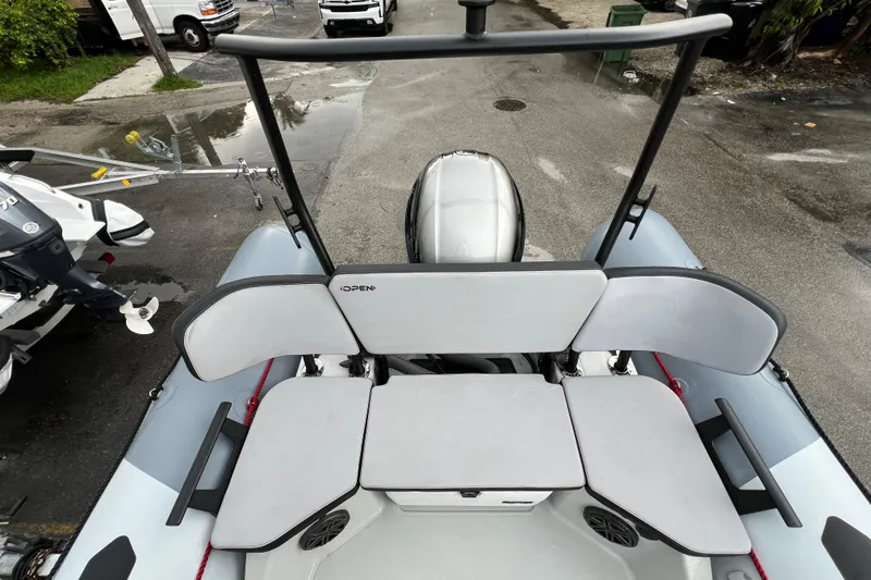 Slide: The Image of 2025 Zodiac Open 5.5 boat interior with seating and motor, parked on pavement. - 4