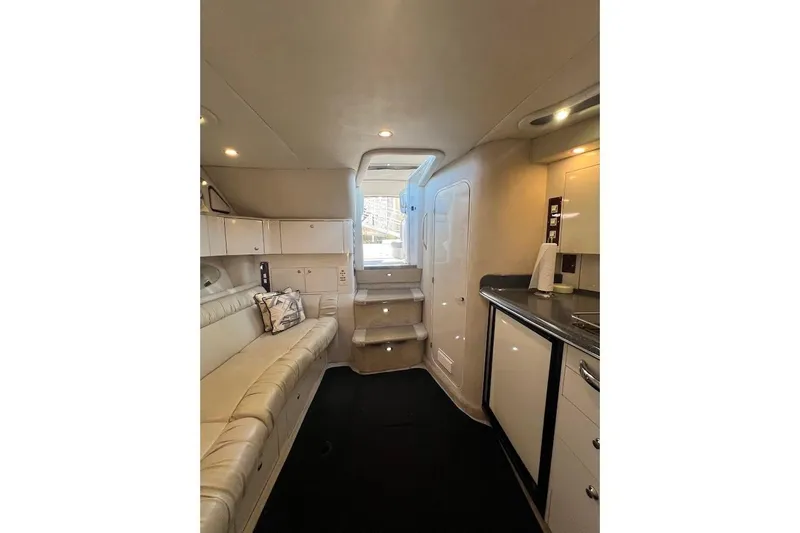 Slide: The Image of Interior of 1997 Sea Ray 330 Express yacht, featuring a cozy seating area and kitchenette. - 11