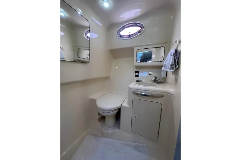 Slide: The Image of 1997 Sea Ray 330 Express bathroom with toilet, sink, mirror, and porthole window. - 20