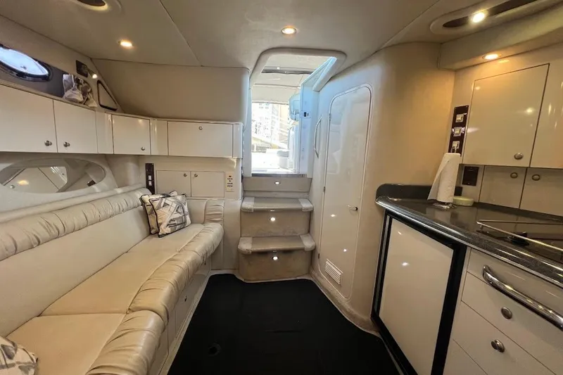 Slide: The Image of Interior of a 1997 Sea Ray 330 Express yacht, featuring a cozy seating area and kitchenette. - 22