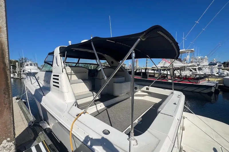 Slide: The Image of 1997 Sea Ray 330 Express boat docked, featuring a spacious deck and canopy under clear blue skies. - 29