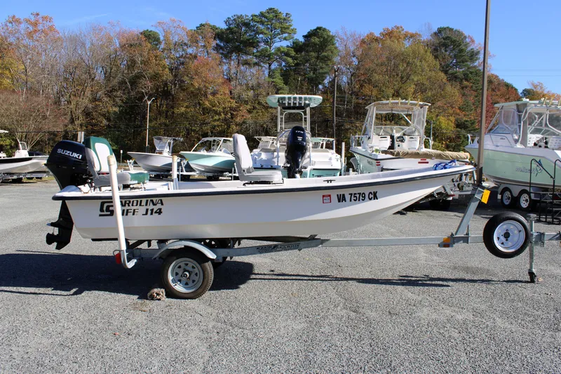 The Image of 2015 Carolina Skiff J14 CC boat on trailer, parked outdoors with other boats. - 0